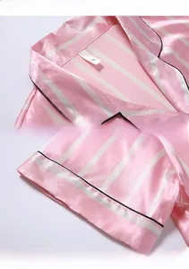 Détail du revers du pyjama en soie à rayures roses avec bordure noire et étiquette