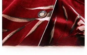Dettaglio macro del tessuto in velluto rosso scuro con motivo a foglie e bottone marrone