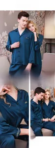 Detail of dark blue silk-like pajamas featuring gold Harmony embroidery on pocket and cuffs