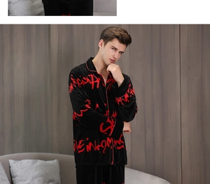 Detail of men's velvet pajama set in black with red graffiti print on comfortable sofa