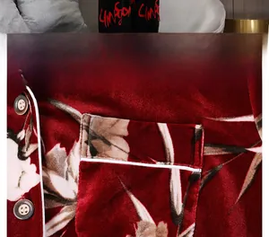 Detail view of burgundy velvet pajama featuring white floral print and chest pocket piping