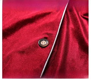 Détail macro d'un pyjama en velours rouge avec passepoil blanc et bouton contrasté