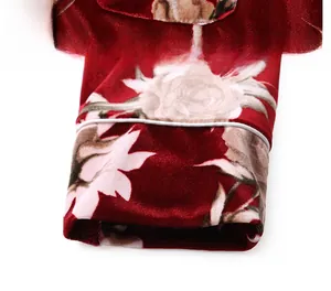 Detail view of red velvet pajamas showing precise white piping and vintage floral patterns
