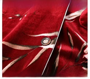 Close-up of velvet pajamas featuring floral print, white piping, and detailed brown button
