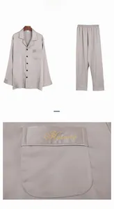 Detailed close-up of grey silk pajamas featuring golden Harmony embroidery on chest pocket