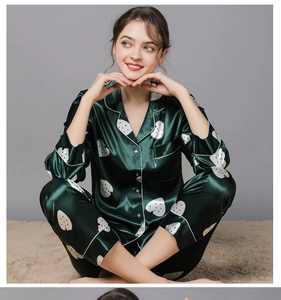 Detail of dark green silk pajamas set with white strawberry prints and contrast piping