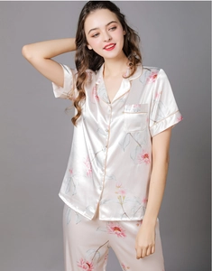 Detail of floral silk pajama set featuring button-up shirt and pink piping accents
