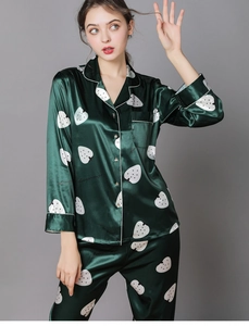 Detail of dark green silk satin pajamas set featuring white strawberry prints and piping