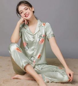 Detailed view of floral and letter print on pale green silk pajamas with satin finish