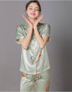 Detail of light green silk pajama set featuring floral print and elegant piping on cuffs
