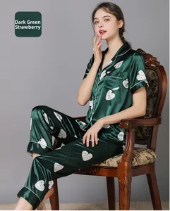 Detail of dark green silk pajamas with white strawberry print and contrast piping