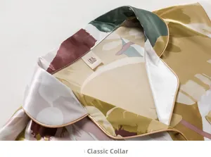 Detail of classic lapel on silk pajamas with tropical leaf print and golden piping trim