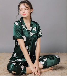Detail of dark green satin pajamas set with white strawberry print and button-up front