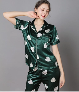 Detail of dark green satin pajama set with strawberry print and white contrast piping