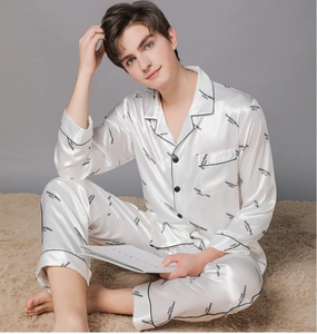 Close-up of pearl white satin pajamas with black piping and stylish brand lettering