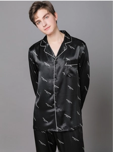 Close-up of black satin men's pajama set with white letter prints and piping detail
