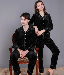 Detail of couple's black velvet pajamas featuring diamond quilted pattern and white piping