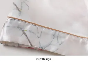 Detail of silk pajama cuff with elegant leaf print and gold piped edge design