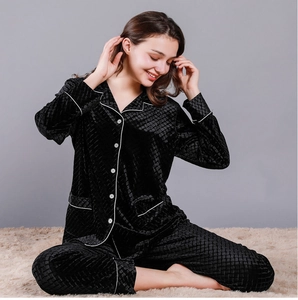 Detailed view of women's black velvet pajamas featuring diamond quilted texture and white piping