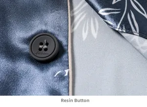 Detail of dark blue silk pajama fabric with white leaf prints and a resin fashion button