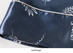 Detailed close-up of dark blue silk pajama cuff with botanical prints and contrast piping