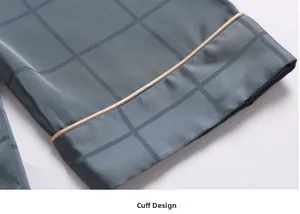 Detail of silk pajama cuff with grey plaid pattern and gold piping craftsmanship