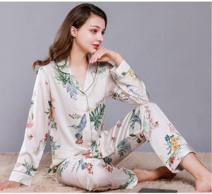 Detail of silk-like satin pajama set with hummingbird floral prints and green piping