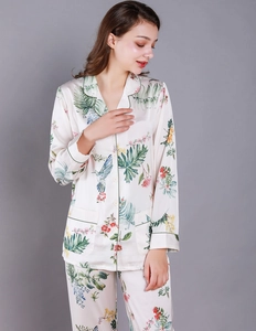 Detail of silk-like pajama set with tropical leaves, floral prints and green piping