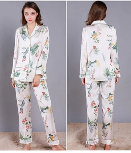 Detail of floral silk pajama set featuring colorful hummingbirds and green piping trim
