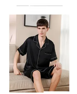Detail of men's black silk-satin pajama set featuring white contrast piping on collar