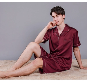 Detail of burgundy satin pajama set featuring white piping and chest pocket texture