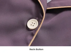 Detail of dark purple silk pajama top with resin buttons and beige piping trim