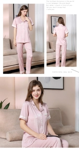 Detail of pink silk satin pajamas featuring floral print and Have A Nice Day embroidery