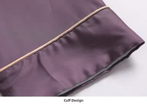 Detailed view of dark purple silk pajama cuffs with golden piping and fine stitching
