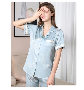 Detail of light blue silk pajamas showing white floral prints and contrast piping trim