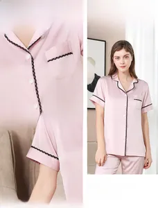 Detail eines rosa Seiden-Pyjamasets mit schwarzer Spitze am V-Ausschnitt und Satin