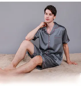 Close-up detail of grey satin pajamas featuring red contrast piping and chest pocket