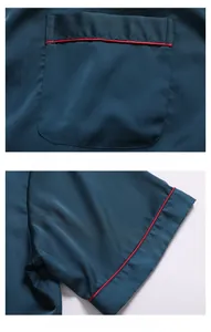 Detail of dark green silk pajama top featuring contrasting red piping on pocket and cuff