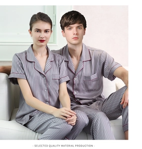 Close-up of silver-gray striped satin pajama set with red trim on models sitting on sofa