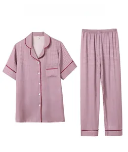 Detailed view of women's dusty pink silk pajamas with houndstooth texture and piping
