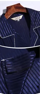 Detail of classic notched lapel and hem on navy blue striped silk-like satin pajamas