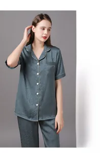 Détail d'un pyjama en soie grise avec motif jacquard floral et finitions passepoilées