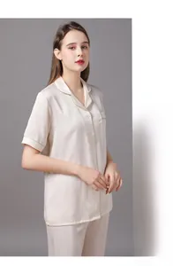 Détail d'un pyjama en satin ivoire avec liseré doré et motifs jacquard à manches courtes