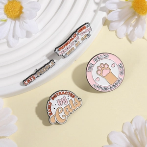 Set of four cute cat enamel pins featuring fun slogans and paw prints on a white stand