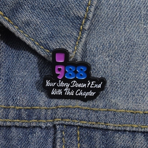 Enamel lapel pin with 'Your Story Doesn't End With This Chapter' text on denim jacket
