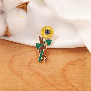 Cartoon sunflower enamel brooch badge with yellow petals and green leaves on white fabric