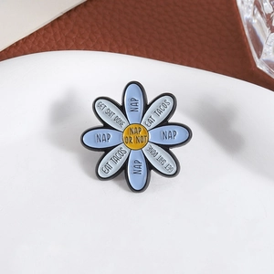 Macro shot of blue daisy enamel pin featuring fun text and polished metal finish