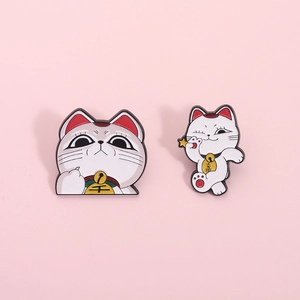 Set of two cute Japanese Maneki Neko cat enamel pins with lucky gold coins on pink background