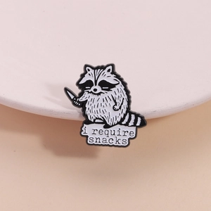 Cute raccoon enamel pin holding a knife with 'i require snacks' text for backpacks