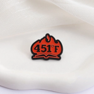 Pin's en émail Fahrenheit 451 avec un livre en feu sur une surface blanche
